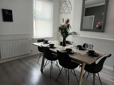 a dining room table with chairs and a vase with flowers at Antonio str Liverpool 6 beds in Liverpool