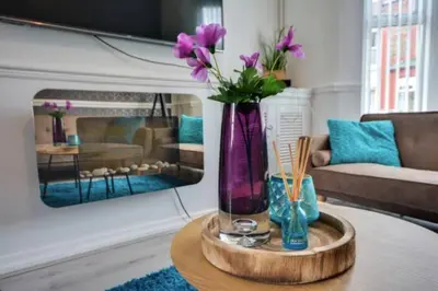 a vase with purple flowers on a table in a living room at Antonio str Liverpool 6 beds in Liverpool