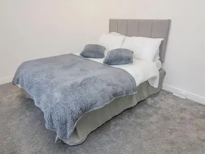 a bed with a gray blanket and pillows on it at 2 Brook Street in Clitheroe