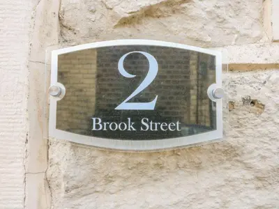 a sign on the side of a stone wall with the number block street at 2 Brook Street in Clitheroe