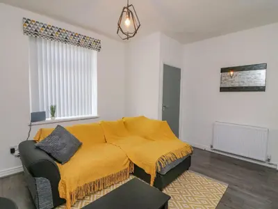 a living room with a couch with a yellow blanket at 2 Brook Street in Clitheroe
