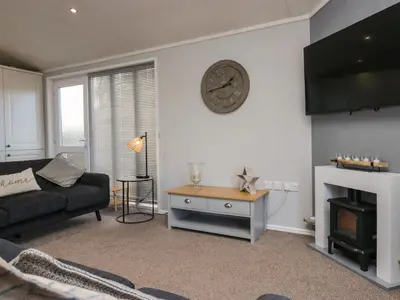 a living room with a couch and a clock on the wall at Lakeside 20 in Carnforth