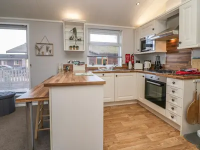 a kitchen with white cabinets and a wooden counter top at Lakeside 20 in Carnforth