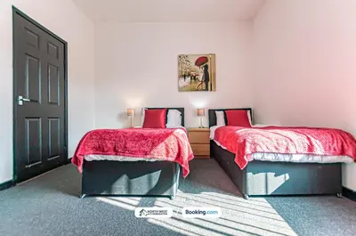 a bedroom with two beds with red sheets and a door at Fully Furnished 3 Bedroom House in Preston with Free Parking in Preston