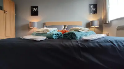 a bed with two blankets and pillows on it at Modern 1-Bed Flat in Wigan in Wigan