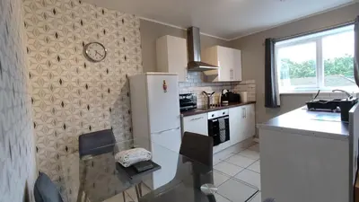 a kitchen with a refrigerator and a table and chairs at Modern 1-Bed Flat in Wigan in Wigan
