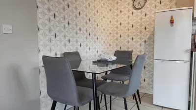 a dining room with a table with chairs and a refrigerator at Modern 1-Bed Flat in Wigan in Wigan
