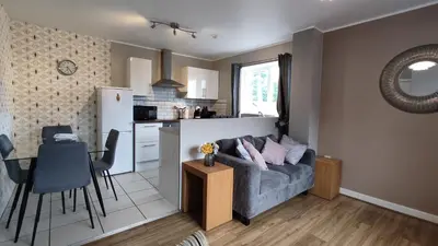 a living room and kitchen with a couch and a table at Modern 1-Bed Flat in Wigan in Wigan
