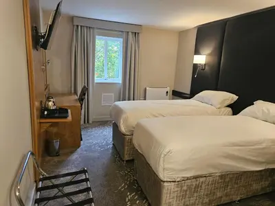 a hotel room with two beds and a window at Wigan Oak Hotel in Wigan