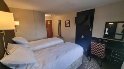 a hotel room with two beds and a tv at Wigan Oak Hotel in Wigan