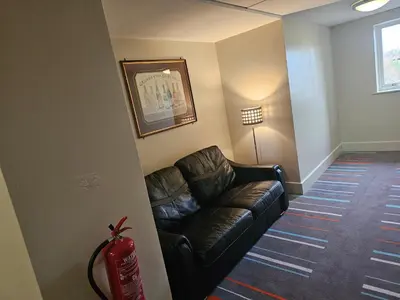 a living room with a leather couch and a fire extinguisher at Wigan Oak Hotel in Wigan
