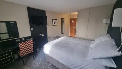 a hotel room with a bed and a chair at Wigan Oak Hotel in Wigan