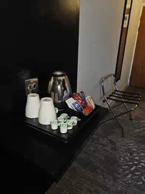 a black table with a coffee pot and cups on it at Wigan Oak Hotel in Wigan