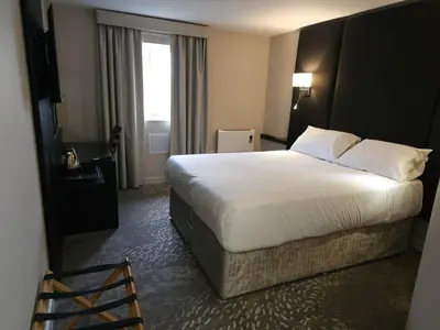 a hotel room with a large bed and a window at Wigan Oak Hotel in Wigan