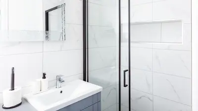 a white bathroom with a sink and a shower at Brown Ball in Barrow in Furness