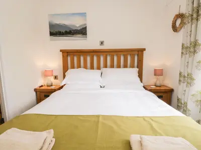 a bedroom with a large white bed with two lamps at Pippin Lodge in Grange Over Sands