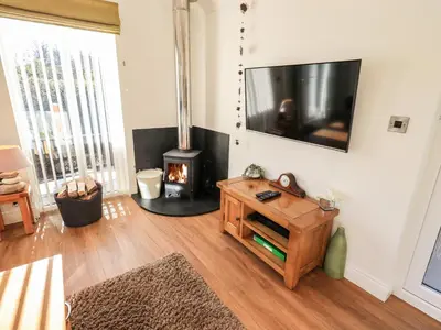 a living room with a fireplace and a tv at Pippin Lodge in Grange Over Sands