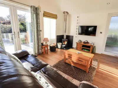 a living room with a leather couch and a coffee table at Pippin Lodge in Grange Over Sands