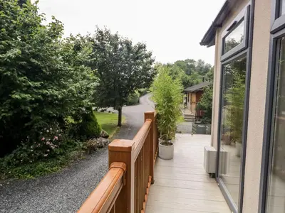 a balcony with a wooden fence and trees at Pippin Lodge in Grange Over Sands