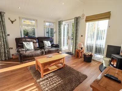 a living room with a leather couch and a coffee table at Pippin Lodge in Grange Over Sands