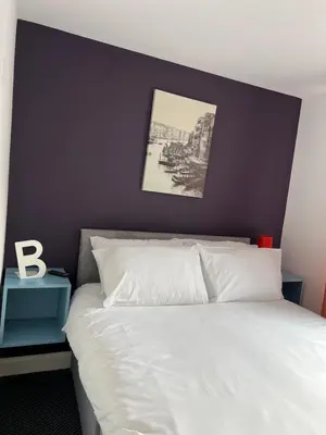 a bedroom with a white bed with a blue accent wall at Tower Suite Serviced Apartment Blackpool in Blackpool