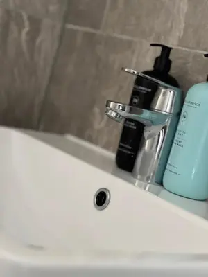 a bathroom sink with a bottle of soap and a soap dispenser at Tower Suite Serviced Apartment Blackpool in Blackpool