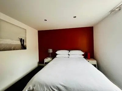 a bedroom with a large bed with a red wall at Tower Suite Serviced Apartment Blackpool in Blackpool