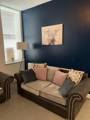 a living room with a couch against a blue wall at Apartments on Albert Road with free parking in Blackpool