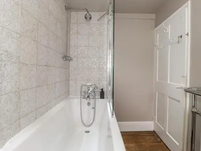 a white bath tub with a shower in a bathroom at Caton Lane House in Grange Over Sands