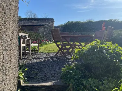 two wooden chairs and a table in a garden at Caton Lane House in Grange Over Sands