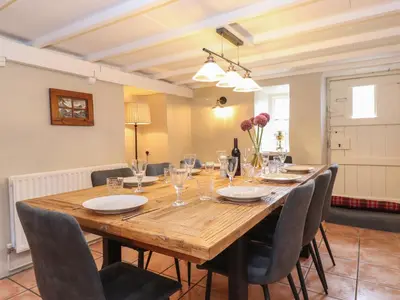 a large wooden table with chairs and a bottle of wine at Caton Lane House in Grange Over Sands
