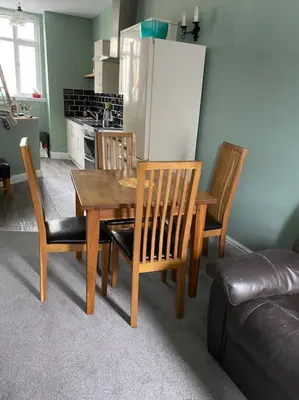 a kitchen with a table and chairs and a refrigerator at The flat at the crooked house in Ulverston
