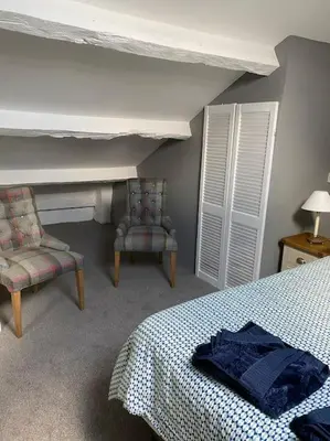 a bedroom with a bed and two chairs in it at The flat at the crooked house in Ulverston