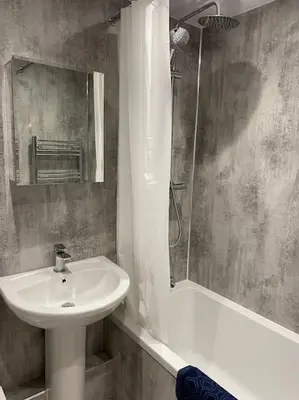 a bathroom with a sink and a mirror and a shower at The flat at the crooked house in Ulverston