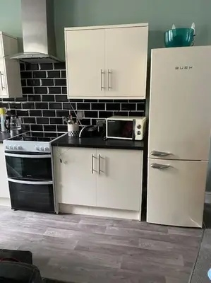 a kitchen with white cabinets and a refrigerator at The flat at the crooked house in Ulverston