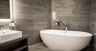 a bathroom with a white tub and a sink at Barton Manor Hotel & Spa; BW Signature Collection in Preston