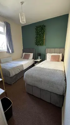 a bedroom with two beds and a green wall at Bronte House - Blackpool in Blackpool
