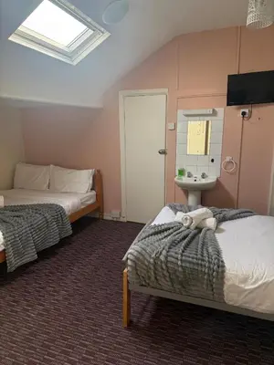 a bedroom with two beds and a sink and a mirror at Bronte House - Blackpool in Blackpool