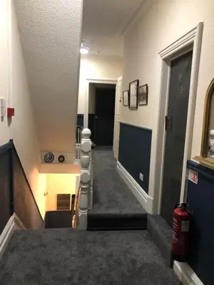 a hallway with stairs leading to a room with a door at Bronte House - Blackpool in Blackpool