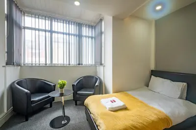 a bedroom with a bed and two chairs and a window at Driftwood Rooms in Blackpool