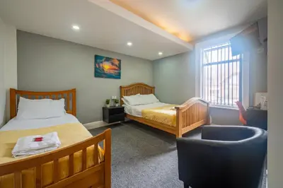 a bedroom with two beds and a chair in it at Driftwood Rooms in Blackpool