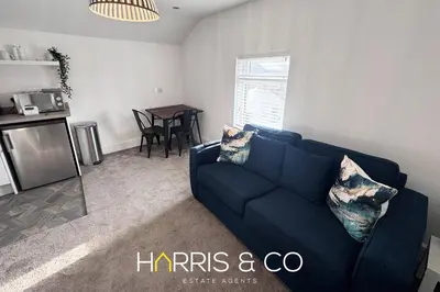 a living room with a blue couch and a table at New Sandpiper Apartments in Fleetwood