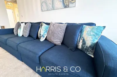 a blue couch with pillows on it in a living room at New Sandpiper Apartments in Fleetwood