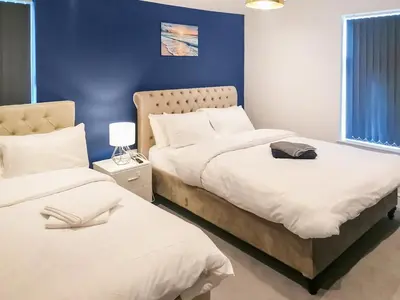a bedroom with two beds and a blue wall at No10 Apartments in Blackpool