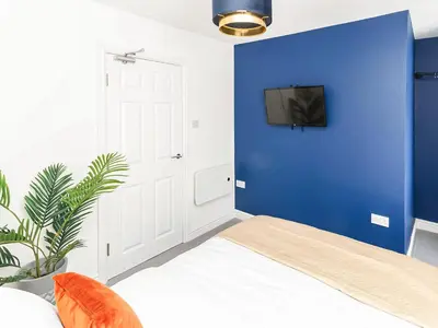 a blue bedroom with a bed and a tv on a blue wall at No10 Apartments in Blackpool