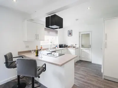 a white kitchen with a counter and a chair at Comfy Spacious Home Near Preston City Centre - Sleeps 6 in Samlesbury