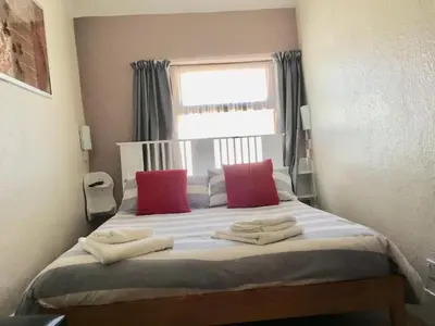 a bedroom with a bed with red pillows and a window at Kirkstall Guest House in Blackpool