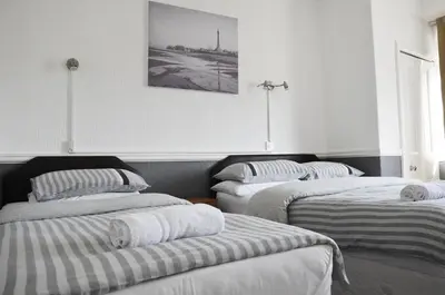 three beds in a room with a picture on the wall at The Gurkha Hotel in Blackpool