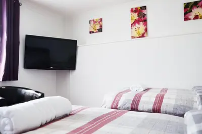 a bedroom with a bed and a flat screen tv on the wall at The Gurkha Hotel in Blackpool
