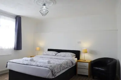 a bedroom with a bed and a black chair at The Gurkha Hotel in Blackpool